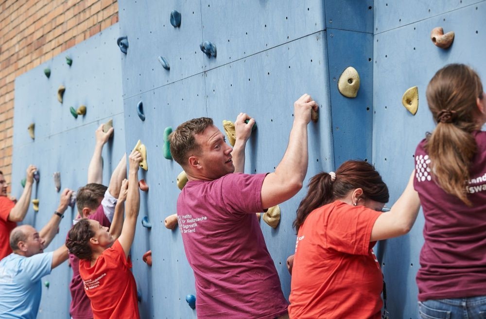 Mitarbeitende an einer Kletterwand